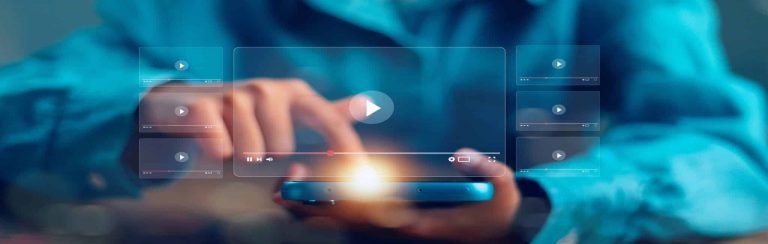 A person taps on a smartphone screen, with translucent digital video player icons and play buttons floating in the air, representing streaming or watching online videos and discovering hidden features like Free church streaming.