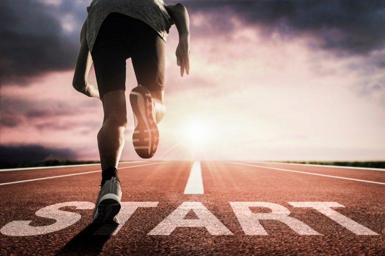 A runner prepares to sprint from a starting line on an outdoor track at sunrise, with "START" boldly painted on the ground—just like an online church ready to stream hope and inspiration as a new day begins.